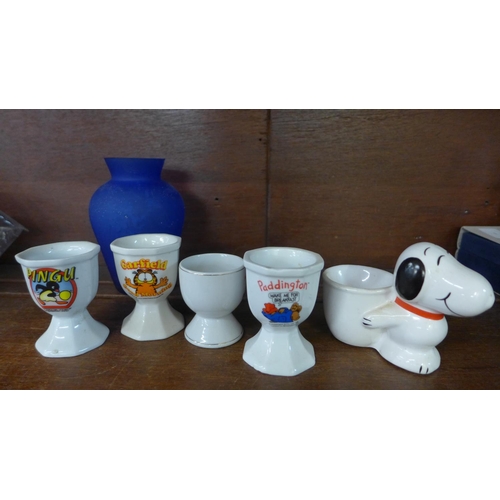 624 - Five collectable egg cups: Paddington, Pingu, etc. and a blue glass vase