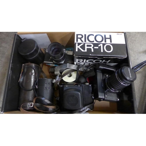 714 - Three 35mm film cameras; Ricoh, Zenit and Praktica, lenses, cases and a tripod