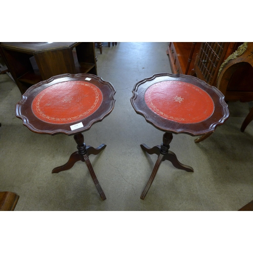 173 - A pair of mahogany and red leather topped tripod wine tables