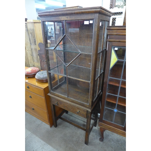 266 - An early 20th Century oak single door display cabinet on stand