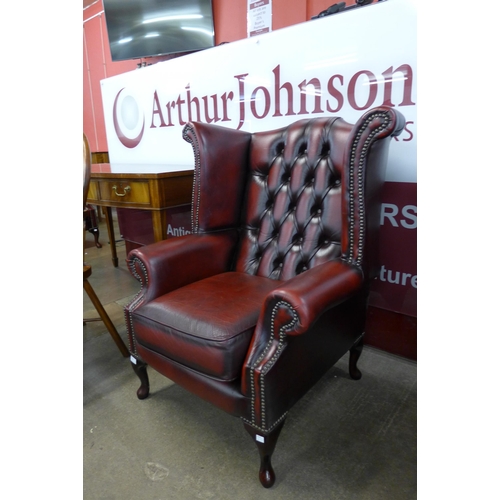 93 - An oxblood red leather Chesterfield wingback armchair