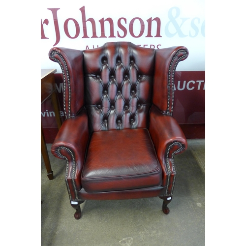 93 - An oxblood red leather Chesterfield wingback armchair