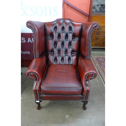 94 - An oxblood red leather Chesterfield wingback armchair