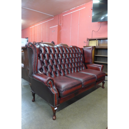 96 - An oxblood red leather Chesterfield wingback settee