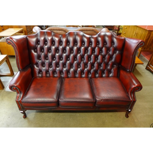 96 - An oxblood red leather Chesterfield wingback settee