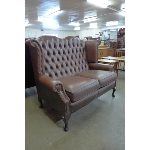 97 - A chestnut brown leather Chesterfield wingback settee