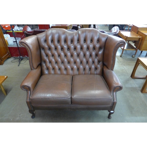 97 - A chestnut brown leather Chesterfield wingback settee