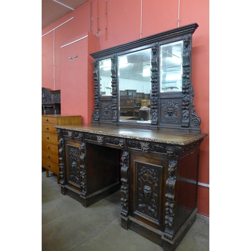 16 - A Victorian Jacobean Revival carved oak green man mirrorback pedestal sideboard