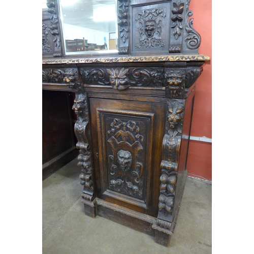 16 - A Victorian Jacobean Revival carved oak green man mirrorback pedestal sideboard