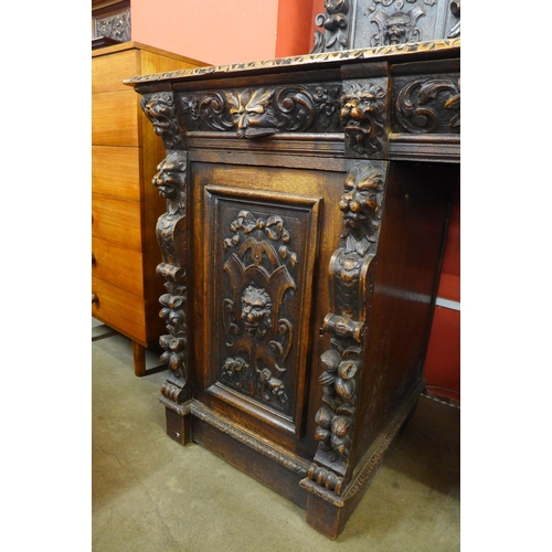 16 - A Victorian Jacobean Revival carved oak green man mirrorback pedestal sideboard