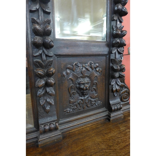 16 - A Victorian Jacobean Revival carved oak green man mirrorback pedestal sideboard