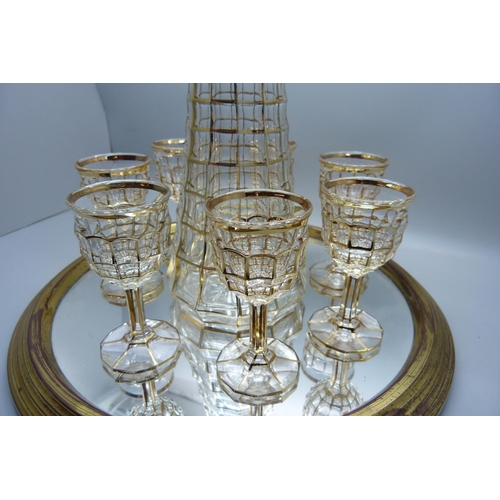 703 - A mid 20th Century gilt drinks set with seven glasses, decanter on a mirrored tray, an Indian pewter... 