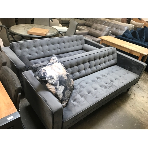 1410 - A pair of grey velvet buttoned back three seater sofas, small repair to one sofa as shown