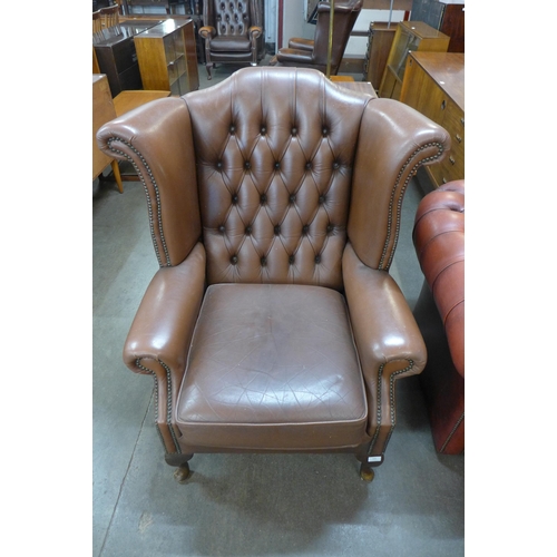 95 - A brown leather Chesterfield wingback armchair