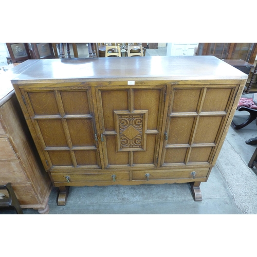 119 - An Art Deco carved oak three door nursery cupboard