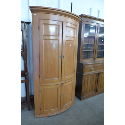 135 - A George III pine bow front freestanding corner cupboard