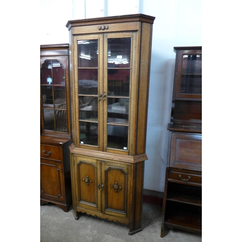 140 - An early 20th Century oak freestanding splay front corner cabinet