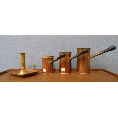 355 - A set of three graduated copper measuring jugs and a chamberstick