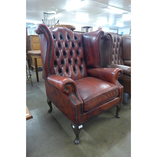 94 - An oxblood red leather Chesterfield wingback armchair