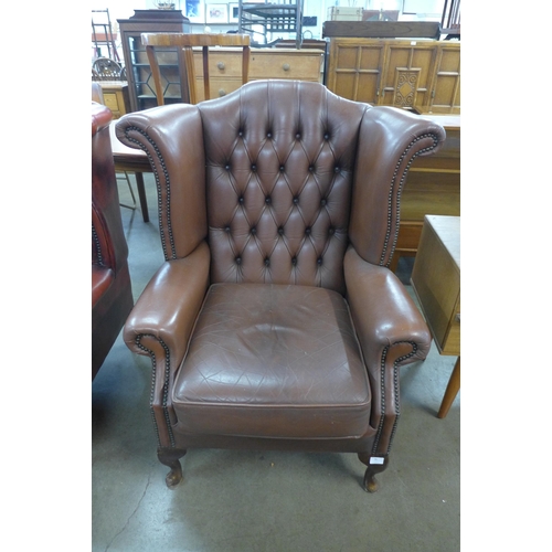 95 - A brown leather Chesterfield wingback armchair