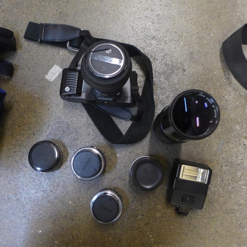 818 - A Canon T70 35mm fim camera, two spare Canon lenses, 24mm and 300mm, an adaptor, Vivitor multiplier ... 