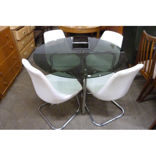 71 - A chrome and smoked glass topped circular dining table and four white vinyl chairs