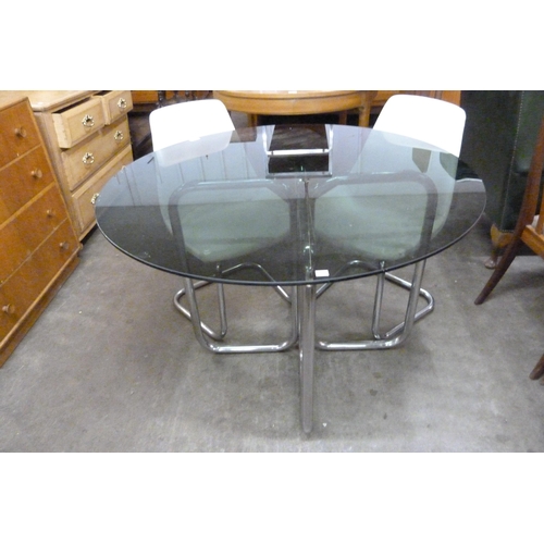 71 - A chrome and smoked glass topped circular dining table and four white vinyl chairs