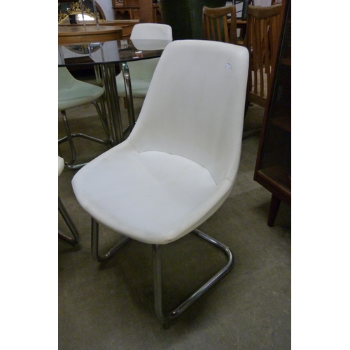 71 - A chrome and smoked glass topped circular dining table and four white vinyl chairs