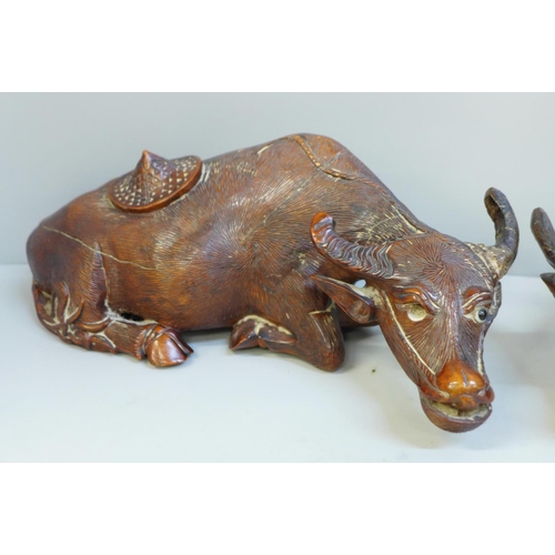 625 - A pair of Chinese carved wooden models of water buffalo, both with damaged horns and splits to body,... 