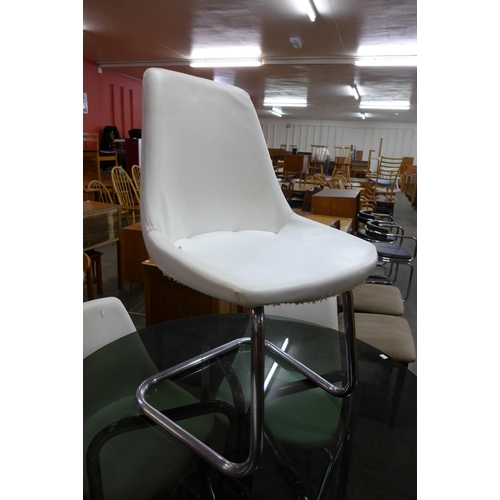 87 - A chrome and smoked glass topped circular dining table and four white vinyl chairs