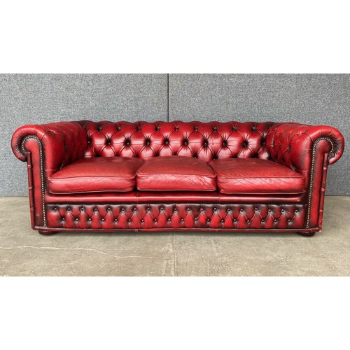 116 - An oxblood red leather Chesterfield settee