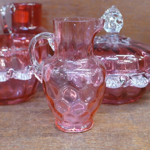 689 - Five items of cranberry glass; two jugs, two pots and a lidded pot, a/f