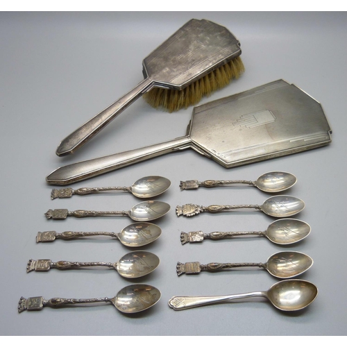 863 - A silver backed Art Deco hand mirror, a brush, a hallmarked silver spoon and nine white metal spoons... 