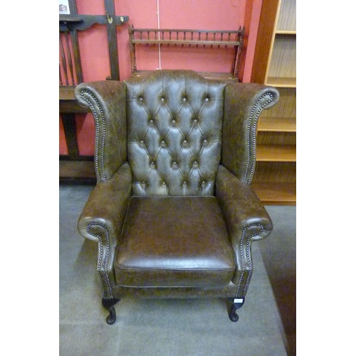 119A - A chestnut brown leather Chesterfield wingback armchair