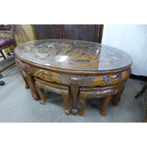 149 - A Chinese carved softwood and glass topped oval nesting coffee table