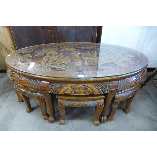 149 - A Chinese carved softwood and glass topped oval nesting coffee table