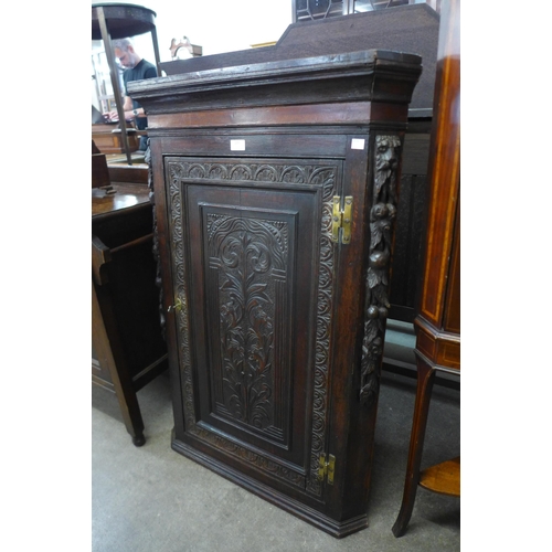 177 - A George III carved oak splay front wall hanging corner cupboard