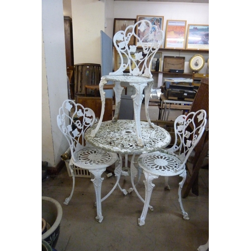 295 - A circular painted cast alloy garden table and three chairs