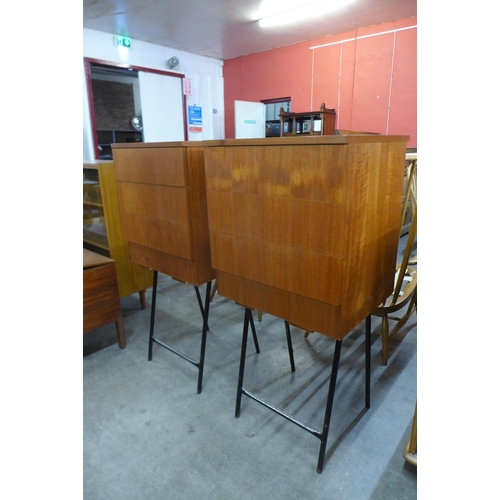 65 - A pair of teak three drawer chests on metal stands