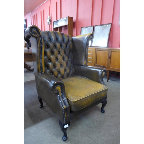 91 - An olive green leather Chesterfield wingback armchair