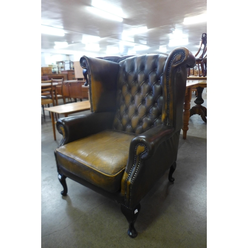 91 - An olive green leather Chesterfield wingback armchair