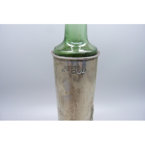 886 - A silver bottle holder with Reynolds angels detail, with a green glass bottle with original label, L... 