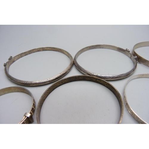 916 - Seven silver bangles and a white metal bangle, large and small sizes