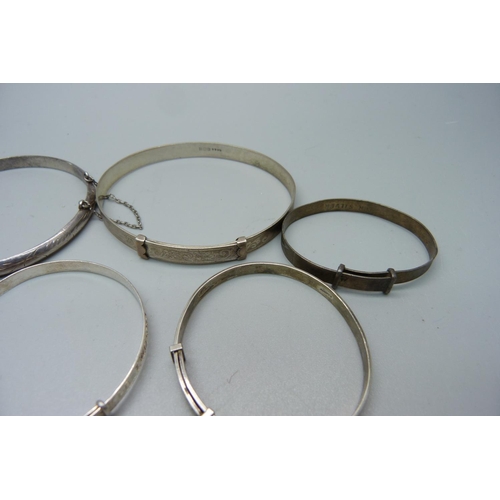 916 - Seven silver bangles and a white metal bangle, large and small sizes