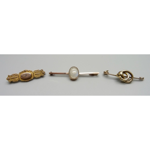 1026 - A 9ct gold and moonstone bar brooch, a 9ct gold brooch and a yellow metal brooch lacking pin, total ... 