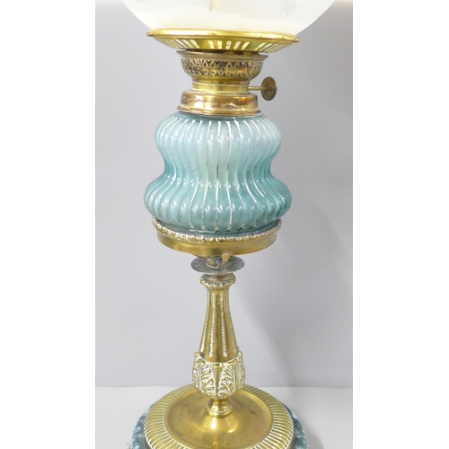 809 - A brass oil lamp with blue glass reservoir and pottery base, replacement shade