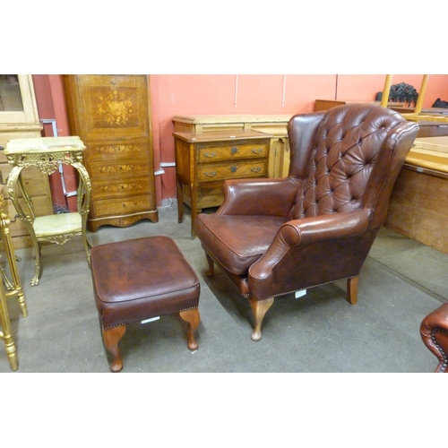 18 - An oxblood red leather wingback armchair and matching footstool