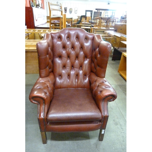 19 - An oxblood red leather Chesterfield wingback armchair