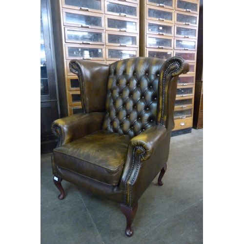 21 - An olive green Chesterfield wingback armchair