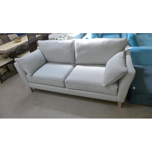 1529 - A stone upholstered three seater sofa on semi exposed hardwood frame